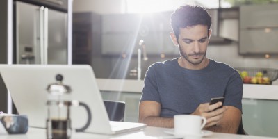 Man texting with cell phone at kitchen table